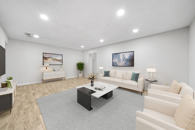 living room featuring light wood-type flooring and a textured ceiling