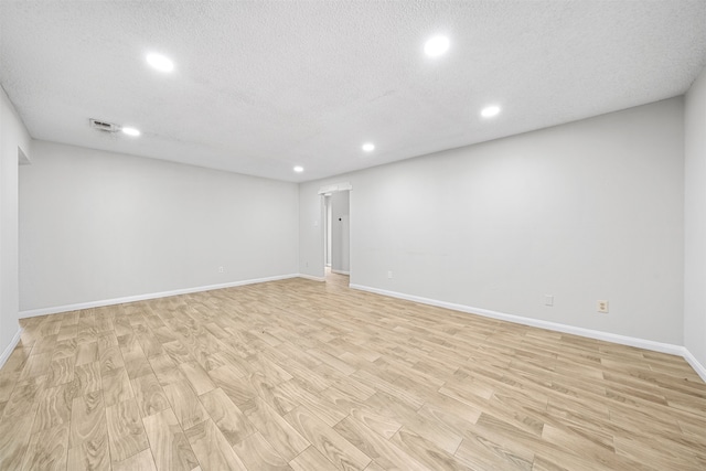 basement featuring a textured ceiling and light hardwood / wood-style floors