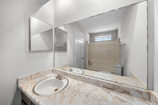 bathroom with washtub / shower combination, vanity, and a textured ceiling