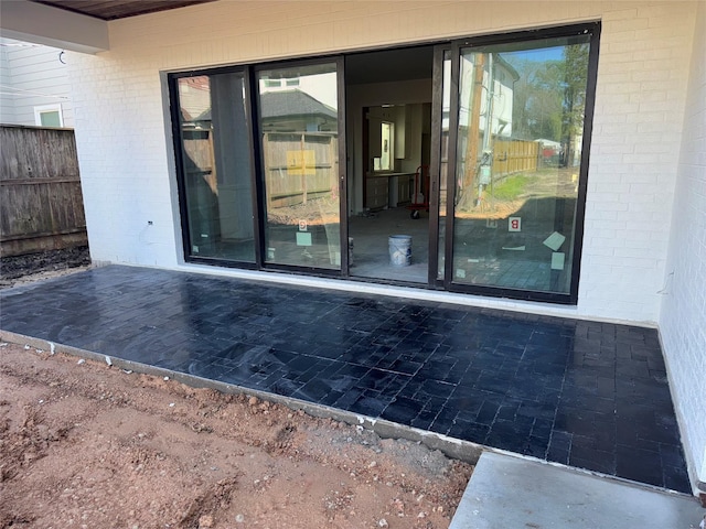 entrance to property with a patio area, brick siding, and fence