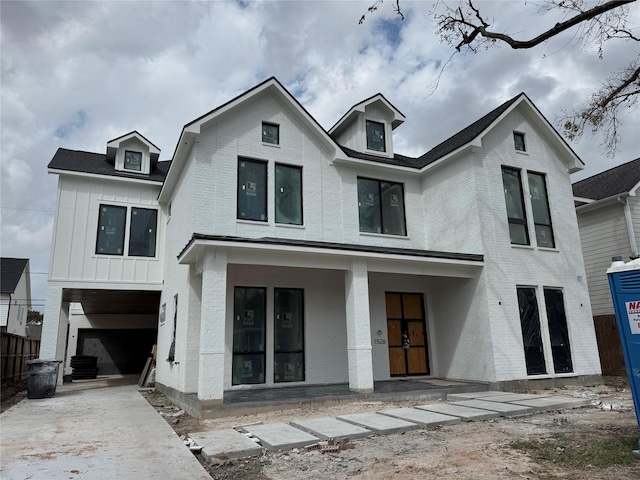 modern inspired farmhouse with brick siding, concrete driveway, covered porch, an attached garage, and board and batten siding