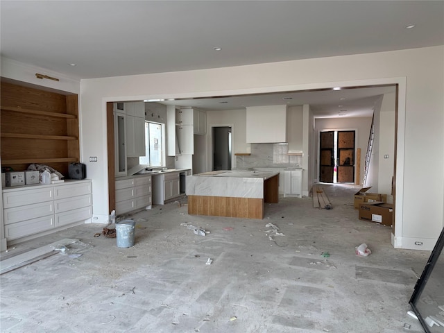 kitchen with open floor plan, white cabinetry, light countertops, and a center island