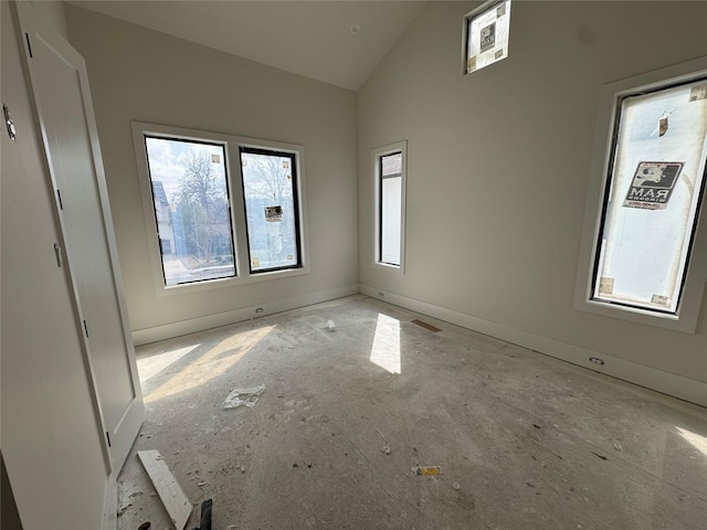 spare room featuring high vaulted ceiling and baseboards