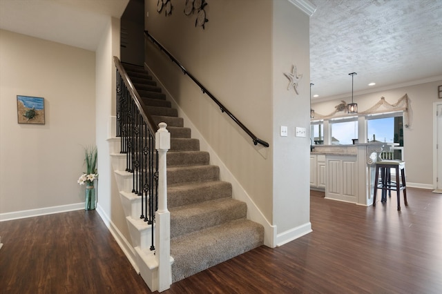 stairs with a textured ceiling, ornamental molding, and hardwood / wood-style flooring