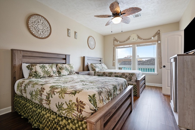 bedroom with ceiling fan, dark hardwood / wood-style floors, and a textured ceiling