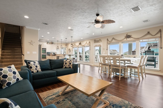 living room with dark hardwood / wood-style flooring, a textured ceiling, ceiling fan, and crown molding