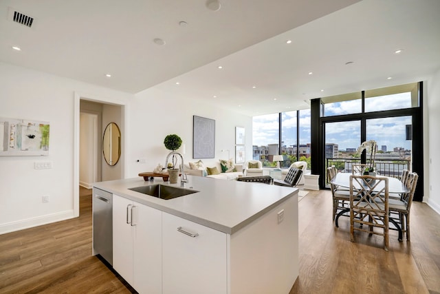 kitchen with white cabinetry, wood-type flooring, sink, and an island with sink