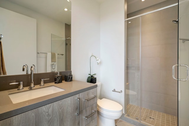 bathroom featuring toilet, vanity, tile patterned flooring, and a shower with shower door