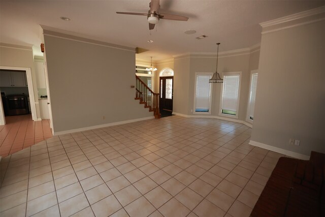 empty room featuring ceiling fan with notable chandelier, light tile patterned flooring, and crown molding