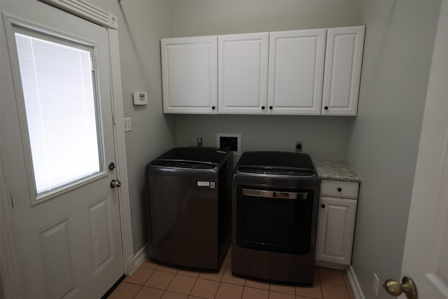 washroom with cabinets, washing machine and dryer, and light tile patterned floors