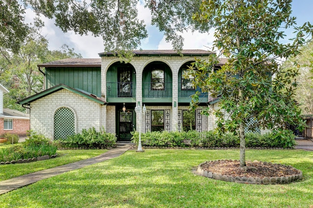 view of front of property featuring a front yard and a balcony