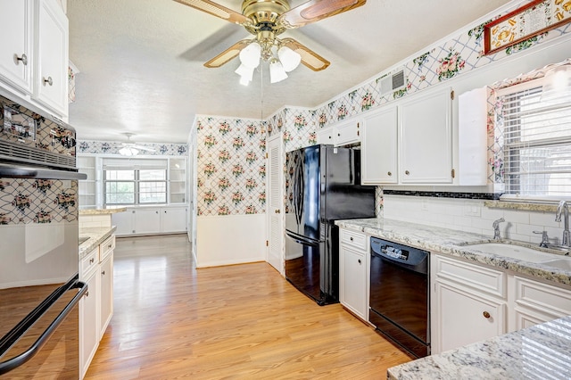 kitchen featuring white cabinetry, black appliances, tasteful backsplash, light stone countertops, and light wood-type flooring