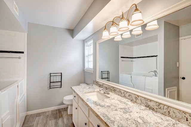 bathroom featuring hardwood / wood-style floors, a washtub, vanity, and toilet