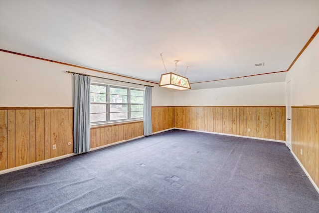 carpeted spare room featuring wooden walls