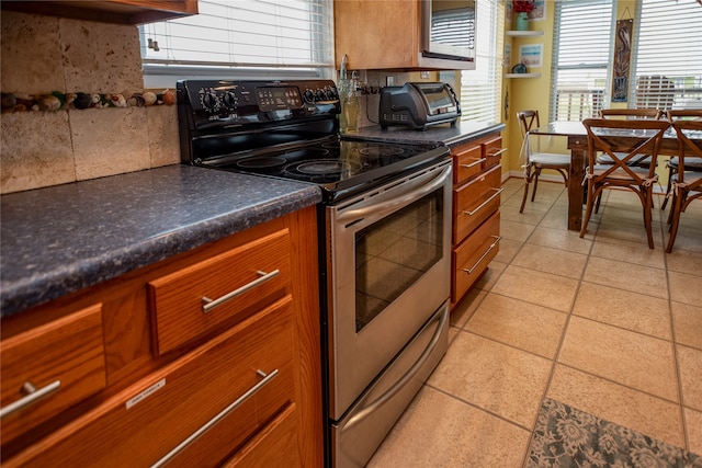 kitchen with stainless steel electric range, light tile patterned floors, and backsplash