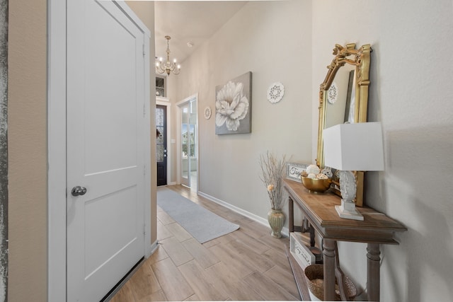 corridor with light hardwood / wood-style floors and a notable chandelier