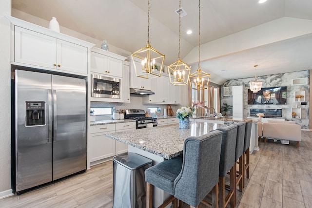 kitchen with appliances with stainless steel finishes, hanging light fixtures, lofted ceiling, and white cabinets