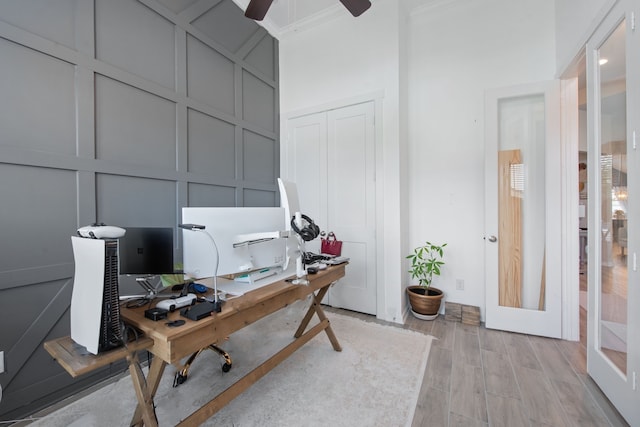 office space featuring ceiling fan, ornamental molding, and light hardwood / wood-style flooring