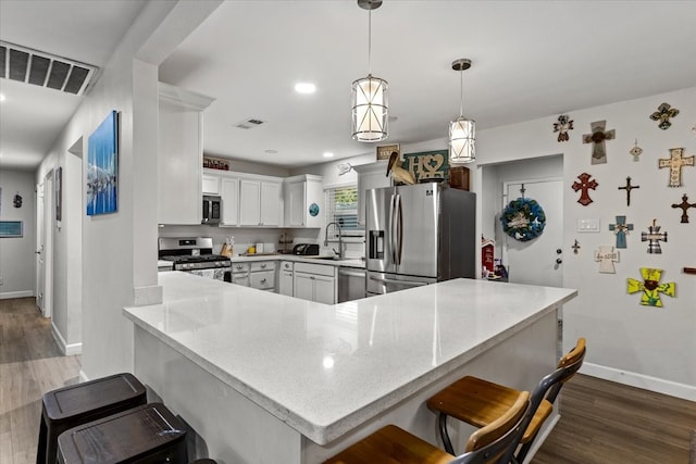 kitchen featuring kitchen peninsula, hanging light fixtures, wood-type flooring, and appliances with stainless steel finishes