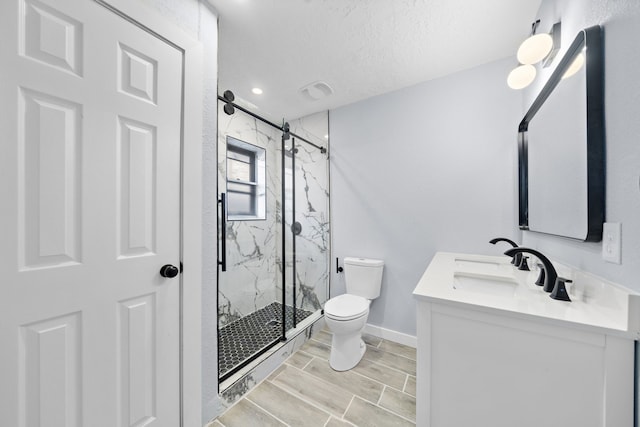 bathroom with an enclosed shower, vanity, a textured ceiling, and toilet