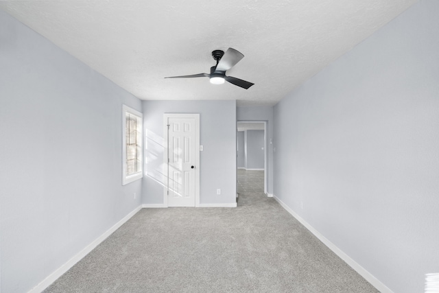 carpeted empty room with ceiling fan and a textured ceiling