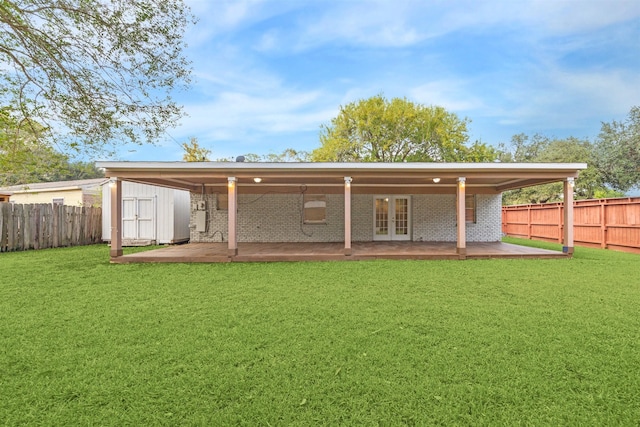 rear view of house featuring french doors, a storage unit, and a yard