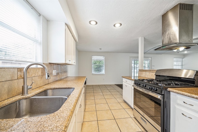 kitchen with white cabinetry, sink, backsplash, wall chimney range hood, and stainless steel gas stove