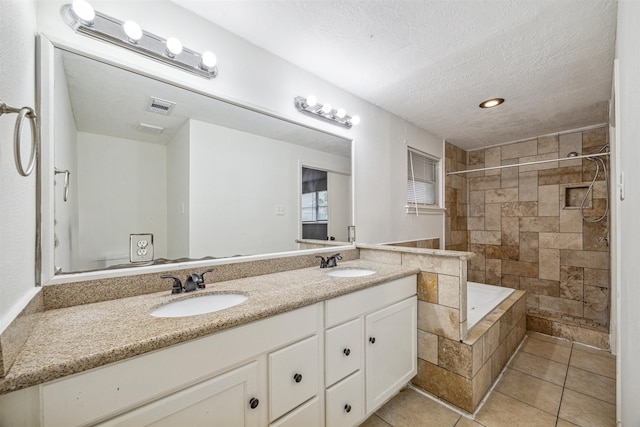 bathroom featuring shower with separate bathtub, vanity, a textured ceiling, and tile patterned flooring