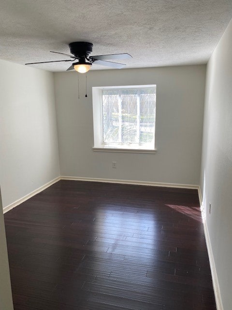 empty room featuring ceiling fan, a textured ceiling, and dark hardwood / wood-style flooring