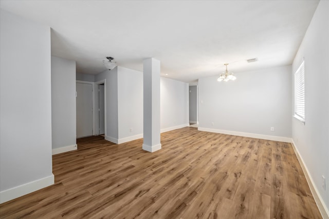 empty room featuring a notable chandelier and light hardwood / wood-style floors