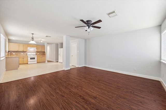 unfurnished living room with light hardwood / wood-style floors, a healthy amount of sunlight, sink, and ceiling fan