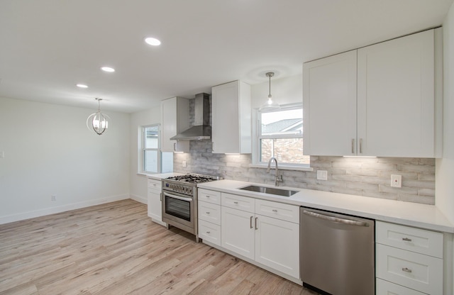 kitchen featuring a wealth of natural light, sink, wall chimney exhaust hood, and stainless steel appliances