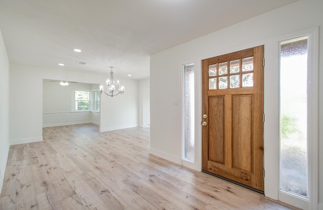 foyer featuring ceiling fan with notable chandelier and light hardwood / wood-style flooring