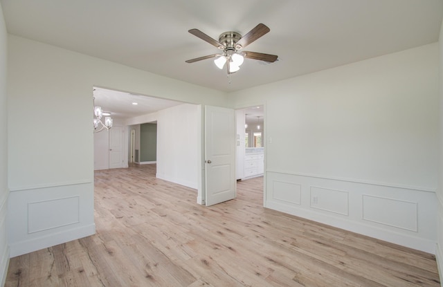 unfurnished room with light wood-type flooring and ceiling fan with notable chandelier