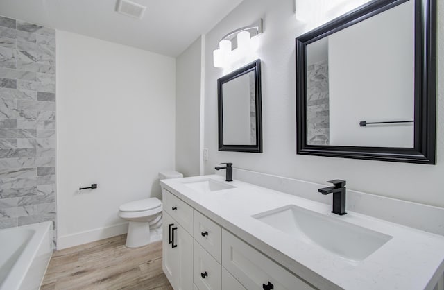 full bathroom with toilet, vanity, tiled shower / bath, and hardwood / wood-style flooring