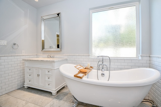 bathroom featuring vanity, a bath, and tile walls