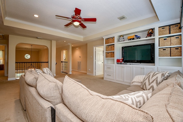 carpeted living room featuring a textured ceiling, a raised ceiling, and ornamental molding