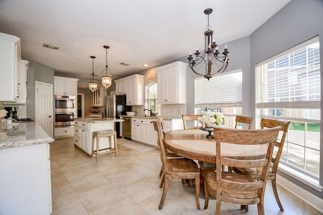 tiled dining space with a chandelier, plenty of natural light, and sink