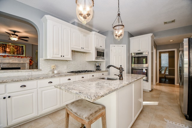 kitchen featuring ceiling fan, sink, stainless steel appliances, decorative light fixtures, and white cabinets