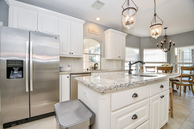 kitchen with pendant lighting, a center island, stainless steel appliances, and a wealth of natural light