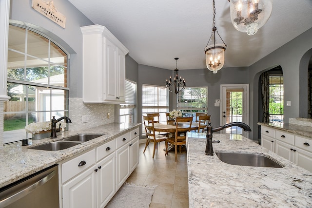 kitchen featuring white cabinets, decorative light fixtures, dishwasher, and sink