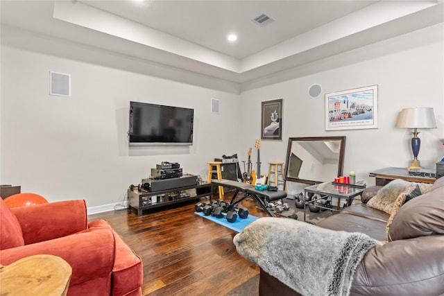 living room with a raised ceiling and dark wood-type flooring