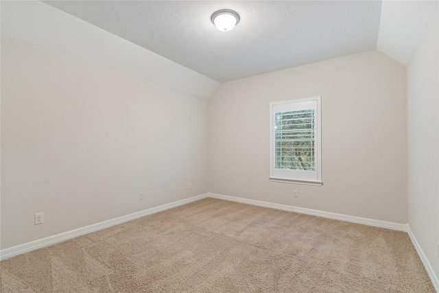 carpeted spare room featuring vaulted ceiling