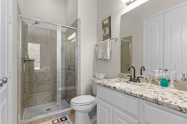 bathroom featuring vanity, toilet, and a shower with shower door