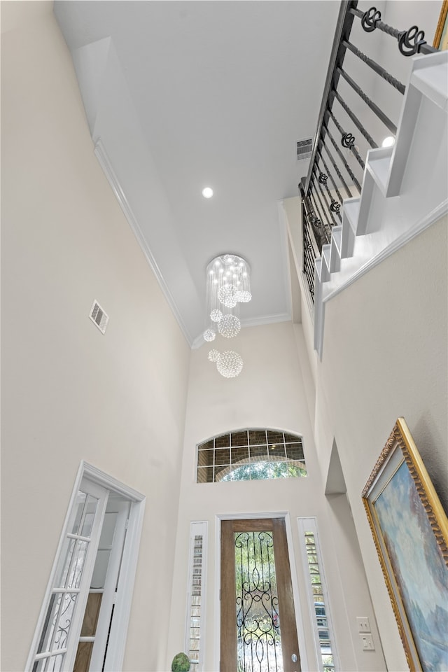 foyer featuring ornamental molding, a high ceiling, and an inviting chandelier