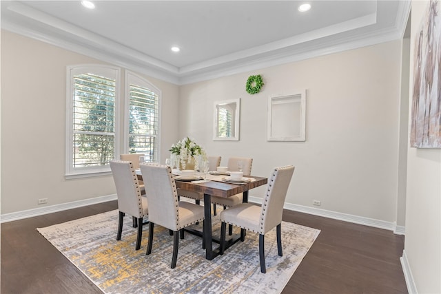 dining area featuring ornamental molding, a tray ceiling, and dark wood-type flooring