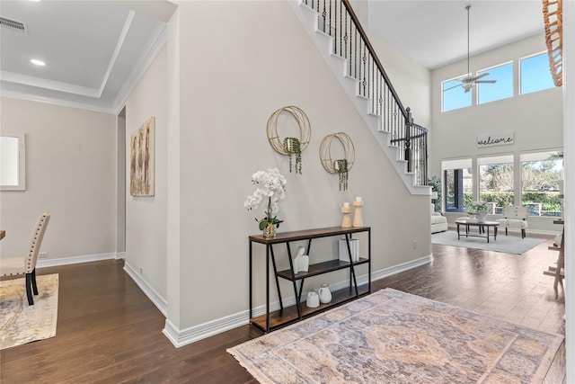 foyer entrance with dark wood-type flooring, ceiling fan, and crown molding