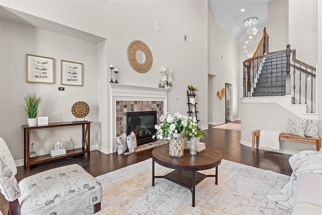 living room featuring a tiled fireplace, hardwood / wood-style floors, and high vaulted ceiling