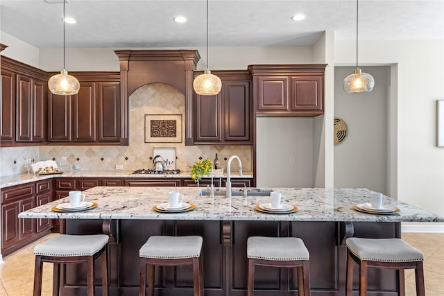 kitchen featuring a kitchen bar, backsplash, pendant lighting, a large island, and light tile patterned flooring