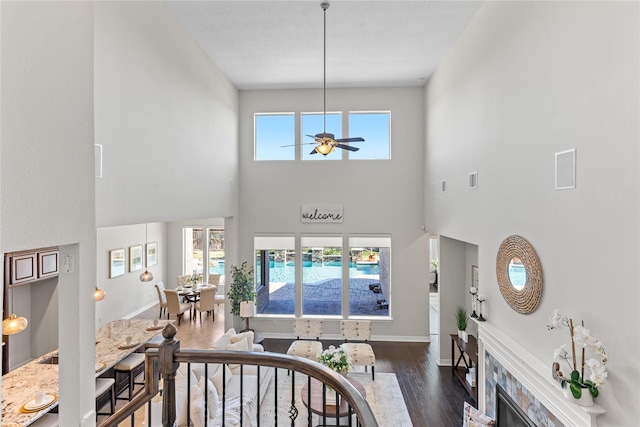 living room with ceiling fan, a healthy amount of sunlight, a tile fireplace, and a high ceiling